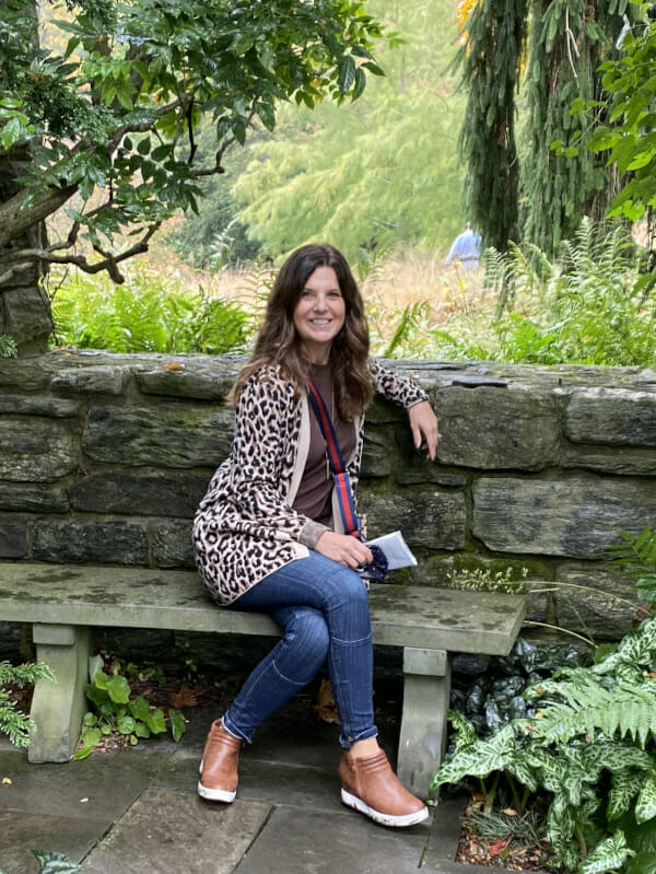 Gina Khalifa sitting on stone bench in lush woods