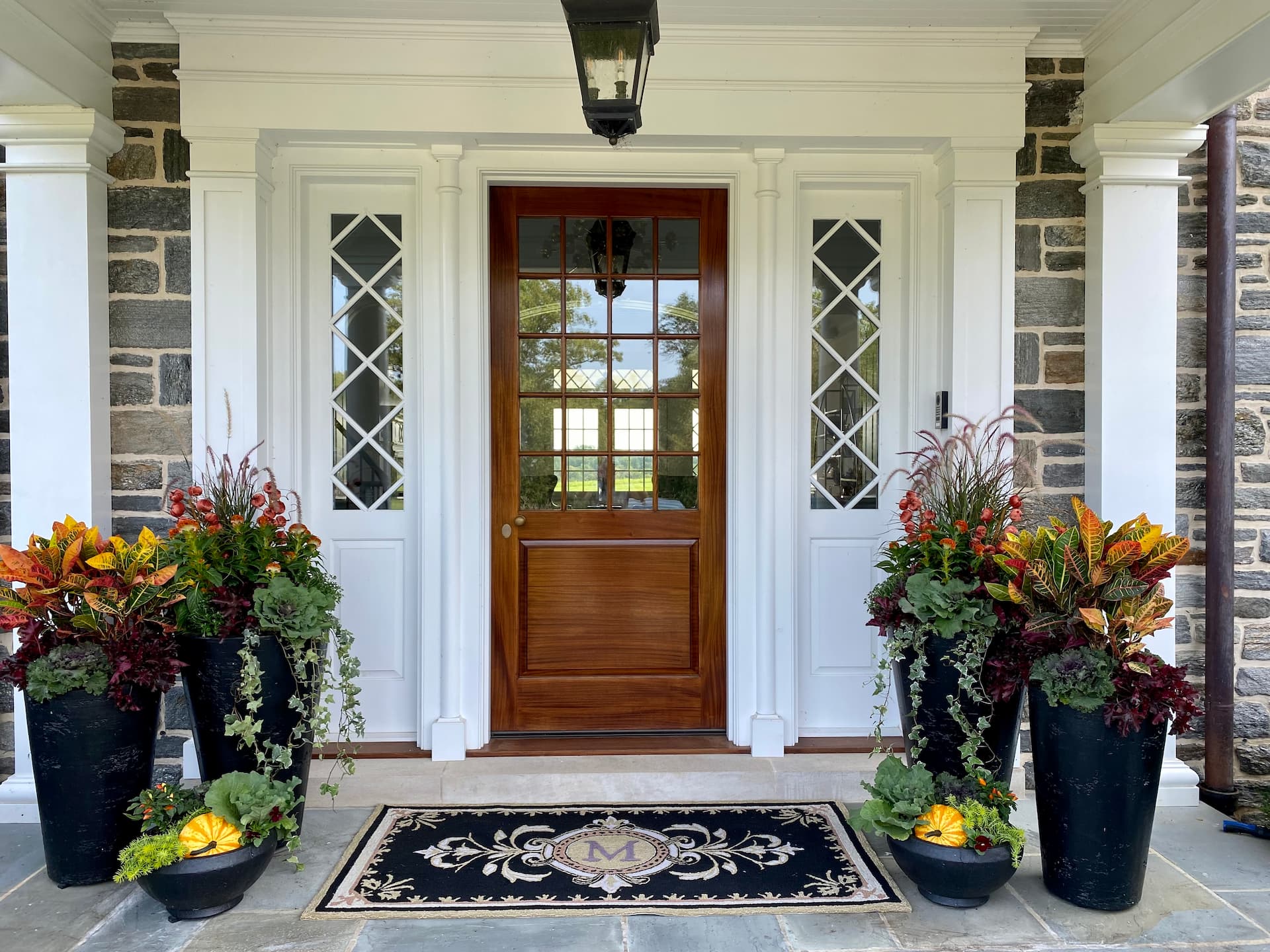 beautiful front door of house with gorgeous urns with autumn plants and flowers